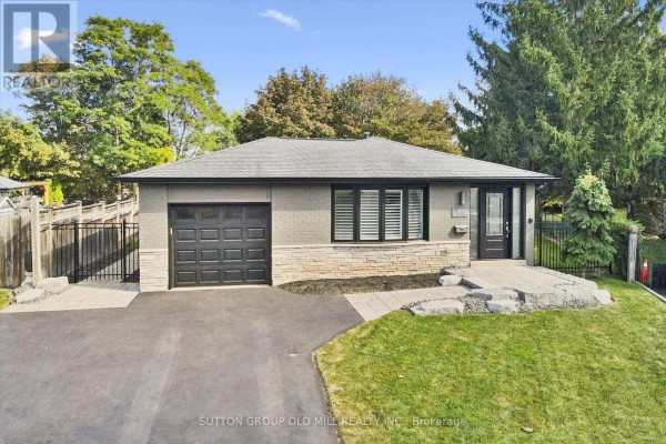 View of a single-story house with a dark grey garage door and a light stone base. - 1233 Michael Crescent, Cambridge