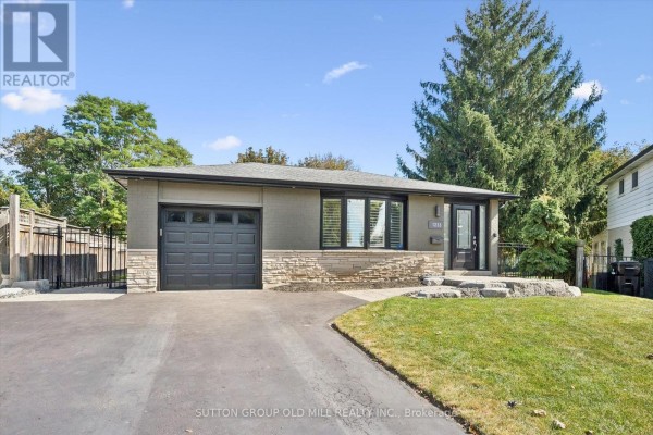 Front exterior of a bungalow with a modern design, featuring a grey garage door and stone accents. - 1233 Michael Crescent, Cambridge