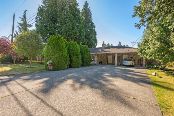 Concrete driveway leading to a covered carport attached to the front of the duplex. - 12332 24 Avenue, Surrey