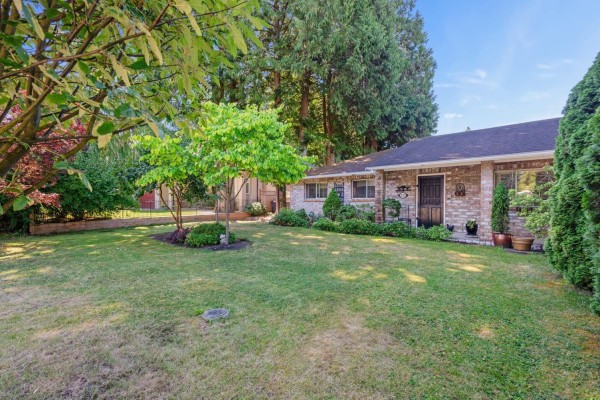 Side view of the duplex showing brick exterior, lawn, and landscaping. - 12332 24 Avenue, Surrey