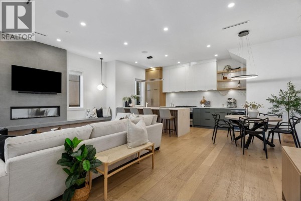 Dining area and kitchen with black table and chairs, island, and white cabinetry. - 1234 E 19th Avenue, Vancouver