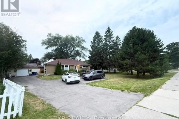 Exterior view of a brick bungalow with a long driveway, garage, and mature trees on the property. - 12376 Tenth Line, Whitchurch Stouffville