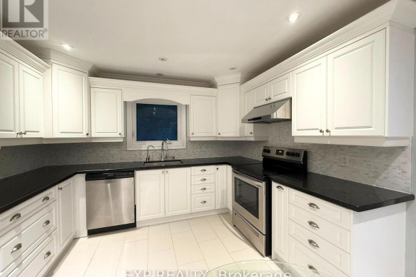 White kitchen with black granite countertops, stainless steel appliances, and a grey tiled backsplash. - 12376 Tenth Line, Whitchurch Stouffville