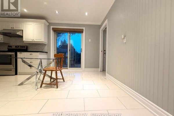 View of the kitchen area showing white cabinets, a glass-top table, sliding glass doors, and a beadboard accent wall. - 12376 Tenth Line, Whitchurch Stouffville