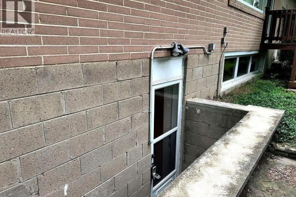 Exterior view of a basement entrance with a concrete foundation and brick wall. - 1238 Donlea Crescent Unit# Bsmt, Oakville