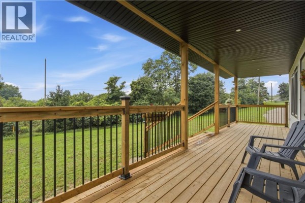 Living room with a grey sofa, stone fireplace, and large window with a view. - 1238 Snyder's Road E, Baden