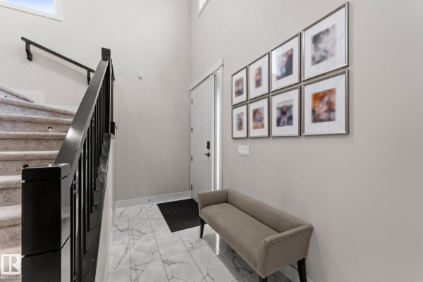 Interior staircase with dark wood railings, carpeted stairs, and marble tile flooring. - 12383 176 Av Nw, Edmonton
