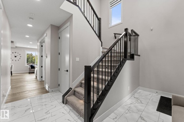 Hallway view of a carpeted staircase with dark wood railings and a bench. - 12383 176 Av Nw, Edmonton