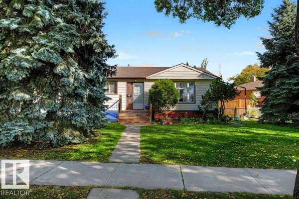 Exterior front view of a beige bungalow with a green lawn and a concrete walkway leading to the door. - 12391 132 St Nw, Edmonton