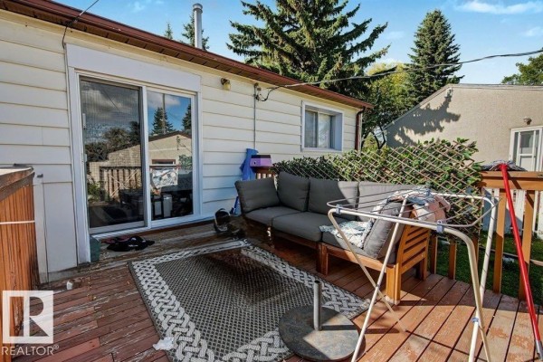 Wooden deck with outdoor furniture, a rug, and a sliding glass door leading into the house. - 12391 132 St Nw, Edmonton