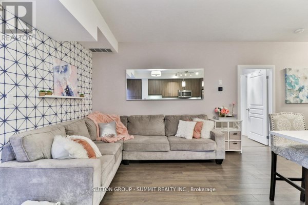 Living room with a patterned accent wall, grey sectional sofa, and island breakfast bar. - 124 - 128 Garden Drive, Oakville
