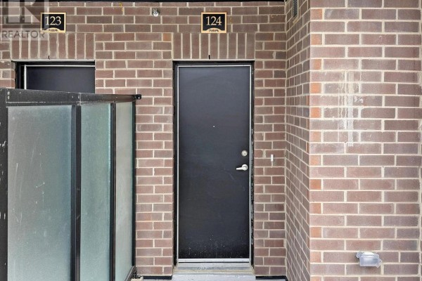 Close-up of townhouse unit 124's black door set in a brick exterior wall. - 124 - 1569 Rose Way, Milton