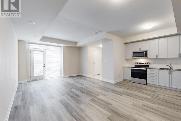 Open concept living area with light grey laminate flooring and modern kitchen. - 124 - 1569 Rose Way, Milton