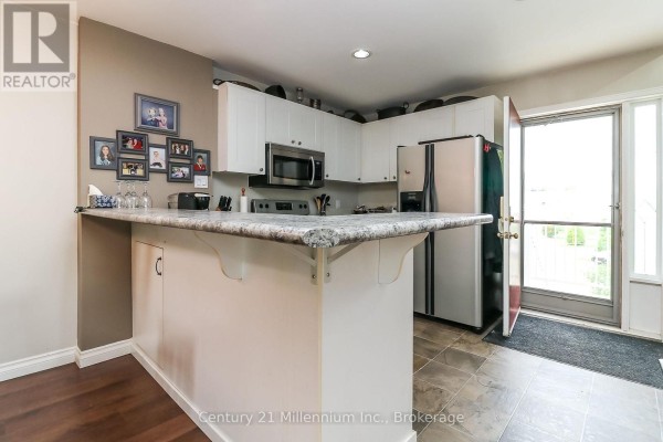 Kitchen corner with white cabinets, stainless steel appliances, and a door to the outside. - 124 - 55 Trott Boulevard, Collingwood
