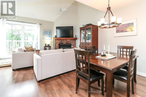 Living and dining area with sofas, fireplace, wooden dining table, and vaulted ceiling. - 124 - 55 Trott Boulevard, Collingwood