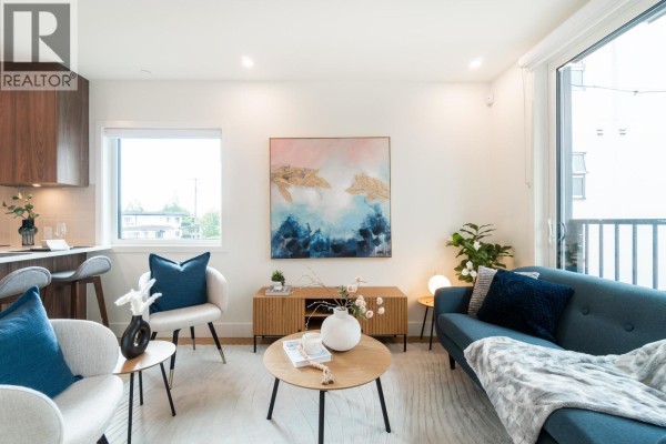 Living room with a sofa, coffee table, and a balcony view through sliding glass doors. - 124 1552 E 3rd Avenue, Vancouver