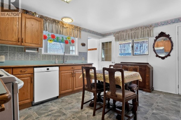 Kitchen with wooden cabinets, dining area, and a mirror on the wall - 124 97c Highway, Ashcroft