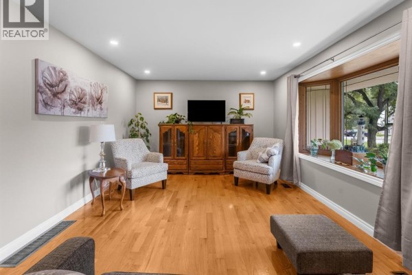 Living room with two patterned armchairs, wooden entertainment center, and bay window with a view of the street. - 124 Allison Avenue, Essex