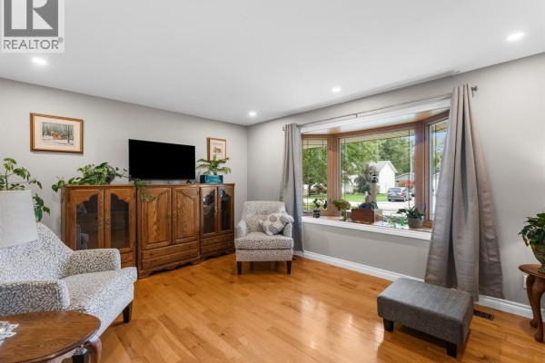Living room seating area with two patterned armchairs, a bay window, and a gray ottoman. - 124 Allison Avenue, Essex