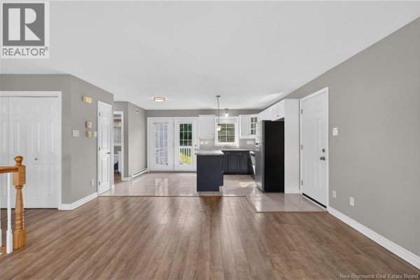 Open-concept living area with a view of the kitchen, dining area, and double doors. - 124 Bahama Street, Dieppe