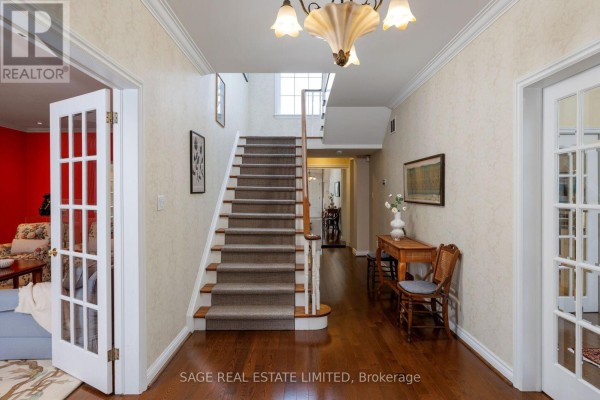 Hallway with hardwood floors, carpeted stairs, chandelier, and glass doors - 124 Blythwood Road Toronto