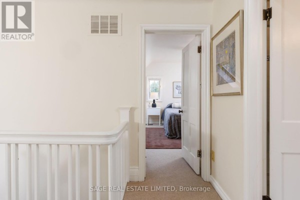 Hallway with white banister and artwork, leading to a bedroom - 124 Blythwood Road Toronto