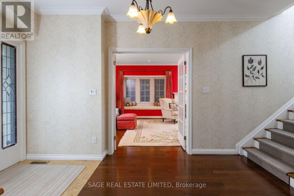 View from the foyer into a room with red walls, a bay window seat, and French doors. - 124 Blythwood Road, Toronto