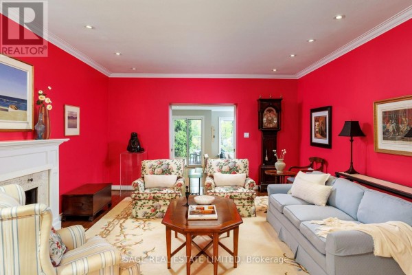 Living room with red walls, floral chairs, blue sofa, and grandfather clock - 124 Blythwood Road Toronto