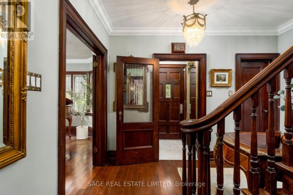 Interior view of a foyer with dark wood doors, trim, and a staircase with a chandelier. - 124 Brentwood Road N, Toronto