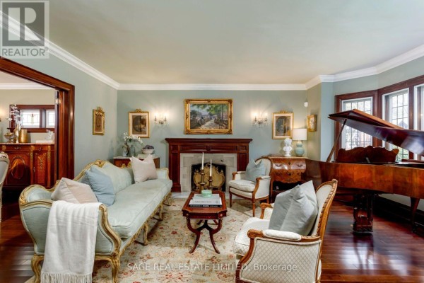 Living room featuring a fireplace, upholstered furniture, a grand piano, and bay windows. - 124 Brentwood Road N, Toronto