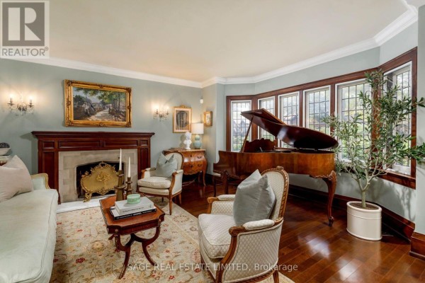 Living room with a fireplace, grand piano, seating, and natural light from bay windows. - 124 Brentwood Road N, Toronto