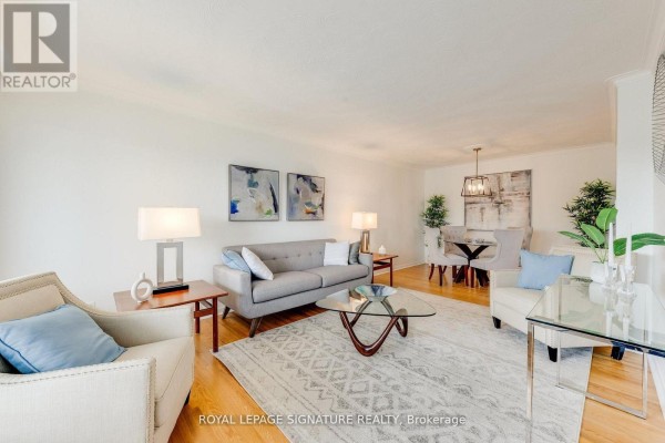 Living room and dining area with grey sofa, beige armchairs, dining table, and chandelier. - 124 Edmonton Drive, Toronto