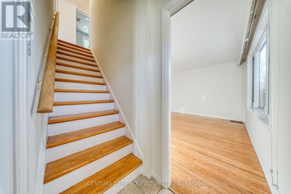 View of an interior hallway showing a white door, wooden floor, and hallway leading to living room. - 124 Homewood Avenue, Toronto