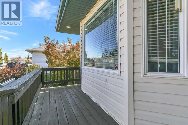 View from the wooden deck overlooking the street and neighboring houses with trees. - 124 Lamont Close, Red Deer