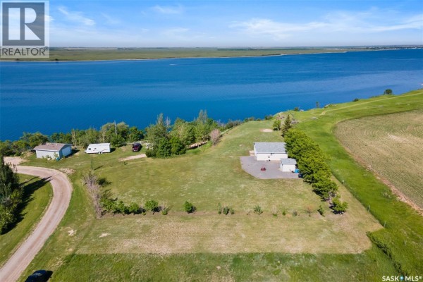 Aerial view of a house, garage, and trailer with a large body of water in the background. - 124 Merle Crescent, Last Mountain Lake