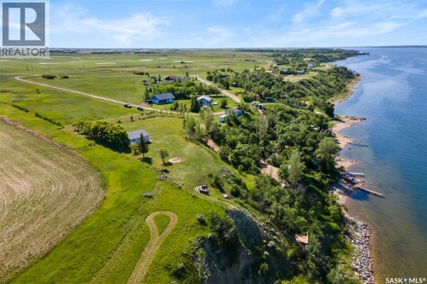 Aerial view of a rural landscape with houses, fields, and a large lake shoreline. - 124 Merle Crescent, Last Mountain Lake