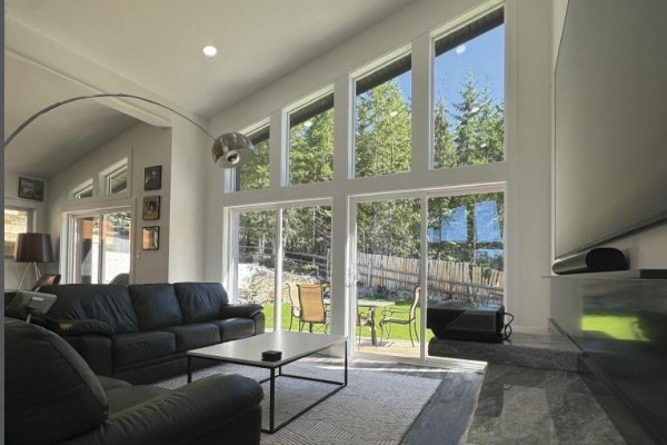 Living room with a large black leather sectional and floor-to-ceiling windows. - 124 Ray Knight Dr, Ladysmith