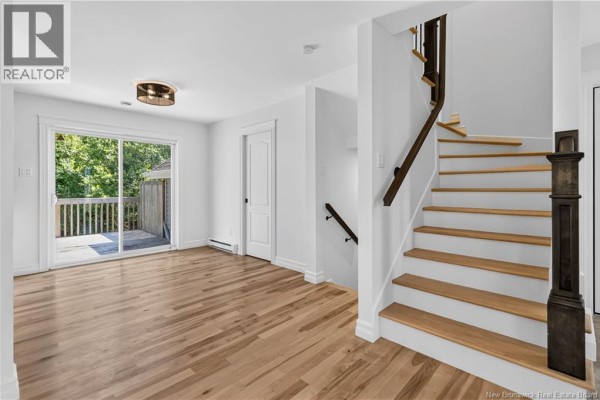 Interior view of a foyer with light wood floors, a staircase, and a double front door. - 124 Rouse Street, Dieppe