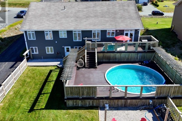 Backyard view of a dark gray house with a wooden deck, above-ground pool, and fence. - 124 Sheldon Drive, Bay Bulls