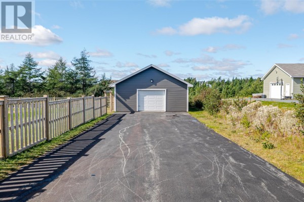 A detached garage with a white door sits at the end of a paved driveway. - 124 Sheldon Drive, Bay Bulls