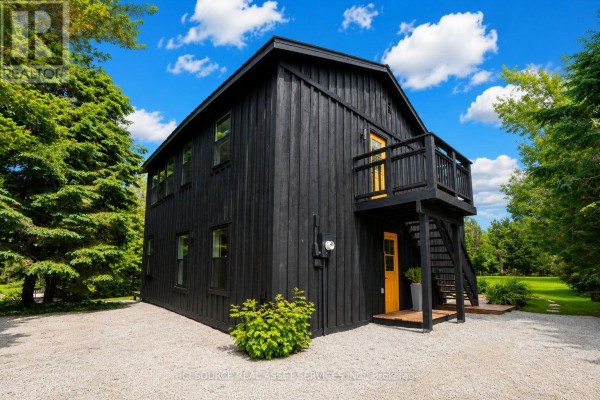 Back view of a black house with a wooden balcony and yellow door. - 124 Tyrol Avenue, Blue Mountains