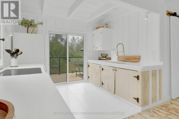 White kitchen with light wood cabinets, modern countertop, and sliding glass door to a deck. - 124 Tyrol Avenue, Blue Mountains