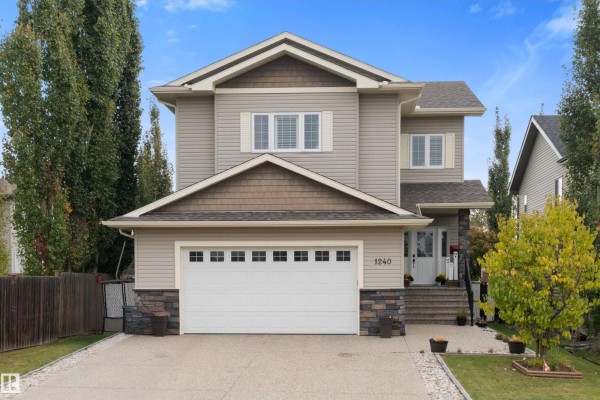 Exterior of a residential house with beige siding, a pitched roof, and a concrete driveway. - 1240 Westerra Cr, Stony Plain