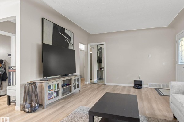 Living room with a television on a media console, and a view into a hallway. - 12408 134 St Nw, Edmonton