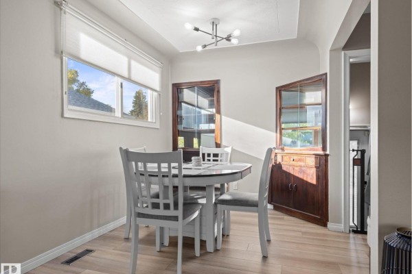 Dining area with a white table and chairs, and a built-in wooden cabinet. - 12408 134 St Nw, Edmonton