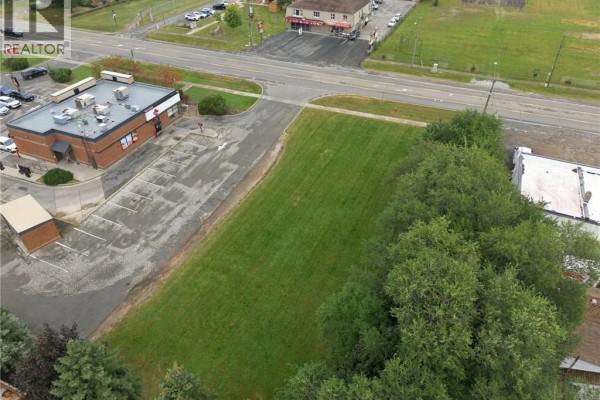 Aerial view of the grassy lot next to a commercial building, parking lot, and road. - 1242 Highway 8, Hamilton