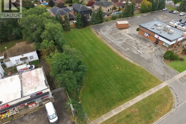 Aerial view of the grassy lot with houses and commercial buildings surrounding it. - 1242 Highway 8, Hamilton