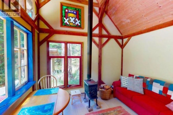 Interior view of the cabin's dining area with a wooden table, chairs, and open door to deck. - 1243/47 Tennyson Rd, Savary Island