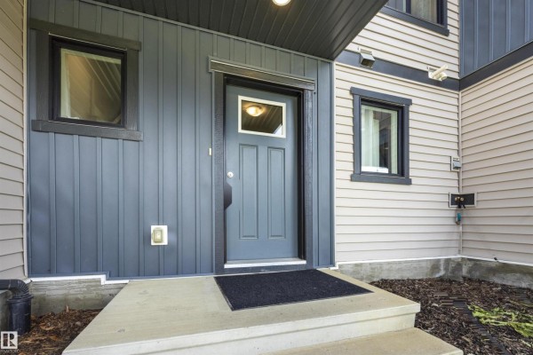 Interior townhouse entryway with a white door, brown patterned mat, and carpeted stairs. - 1246 Aster Bv Nw, Edmonton
