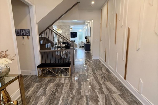 Hallway with marble tile flooring, wall decor, and view into the living and dining area. - 1246 Pondside Trail, Oakville